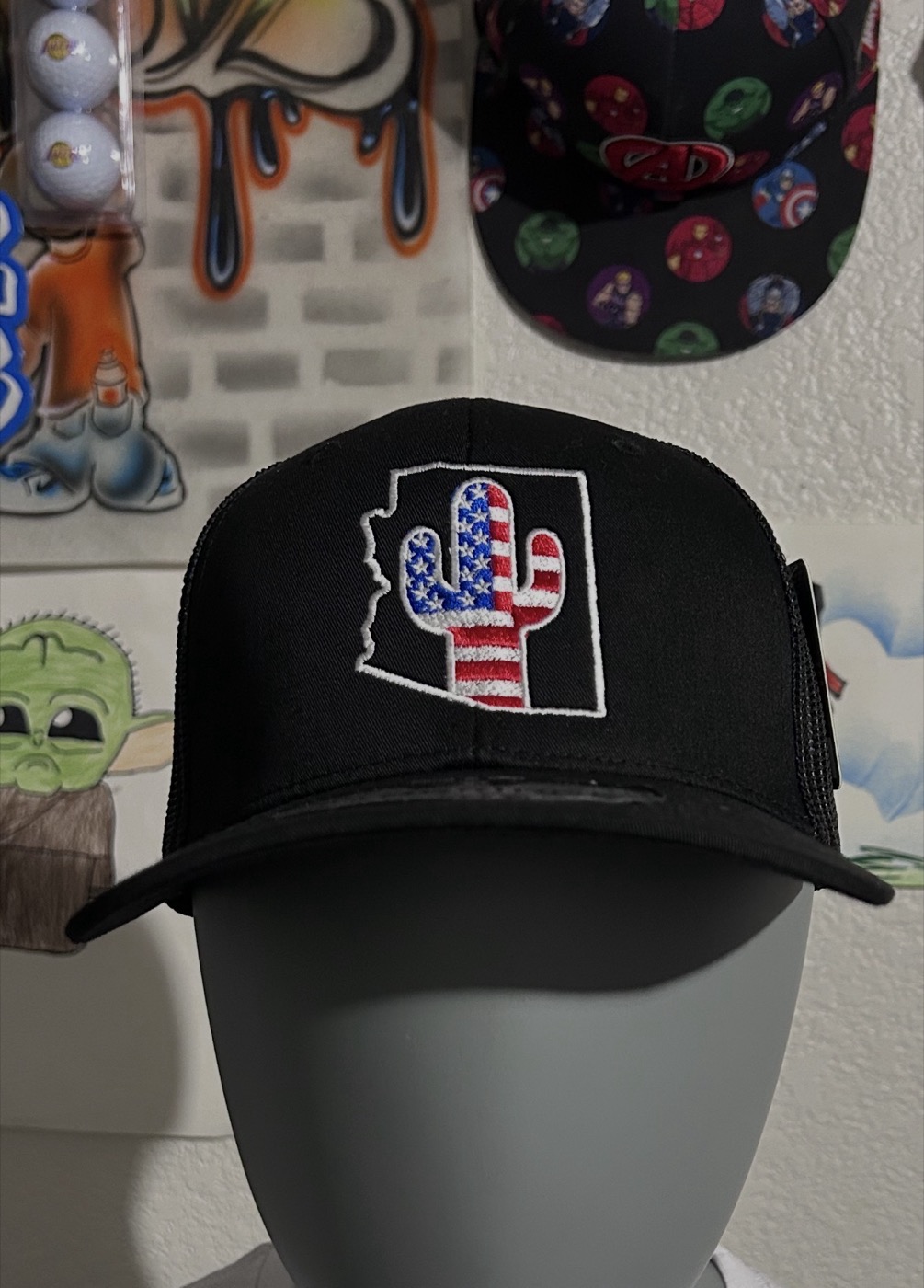 Black trucker cap with an Arizona-shaped cactus patch in flag colors