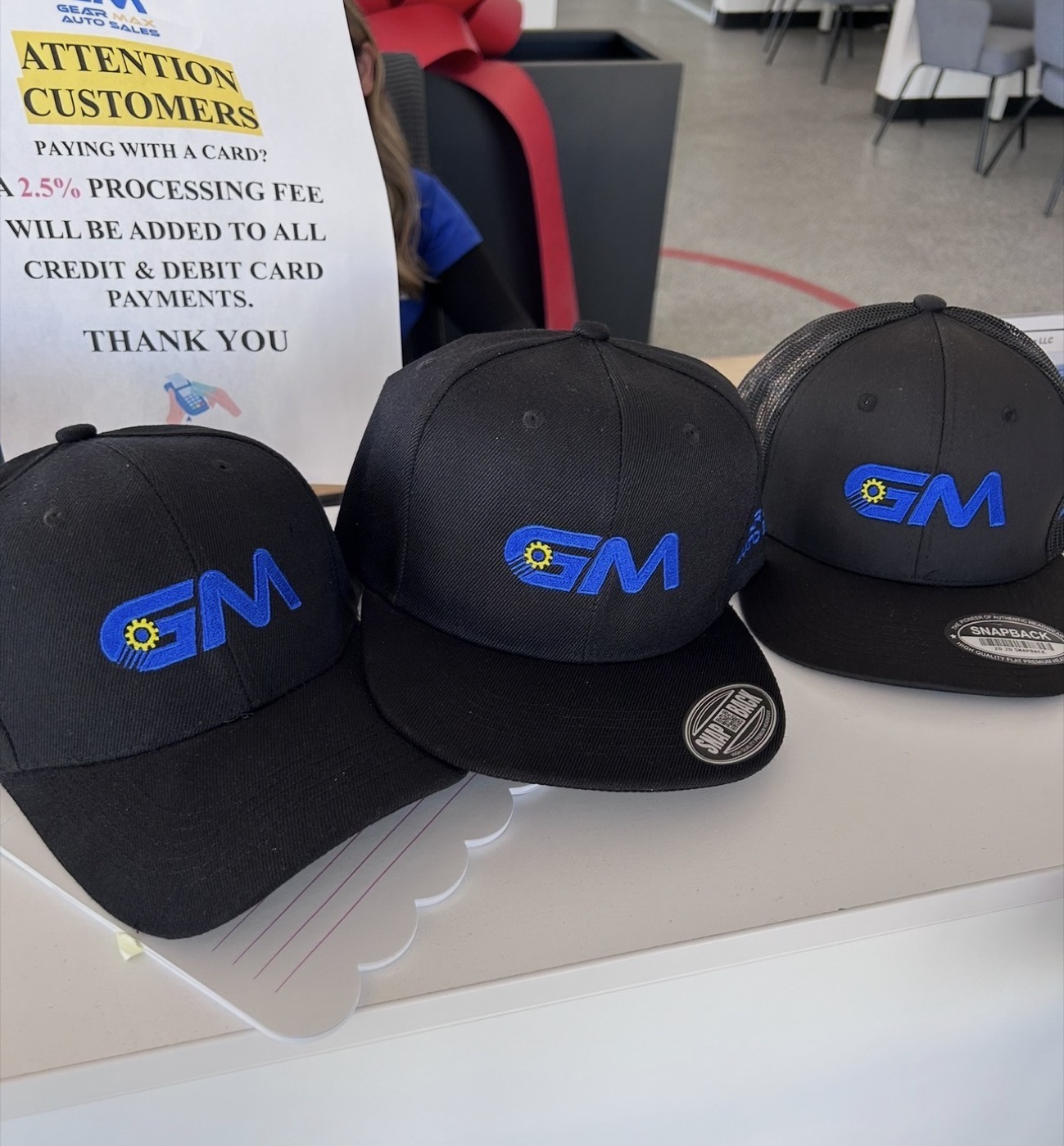 Black caps with the Gear Max Auto Sales gear logo in blue and yellow